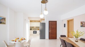 Ein moderner Essbereich mit einem für das Frühst ück gedecktem Tisch, einer Küche im Hintergrund und einer Holztür.