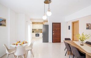 Uma área de refeições moderna com uma mesa posta para o café da manhã, uma cozinha ao fundo e uma porta de madeira.