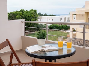 A balcony with a round table, two glasses of orange juice, a potted plant, and a newspaper. - Maris Apts Kato Gouves (Kato Gouves)