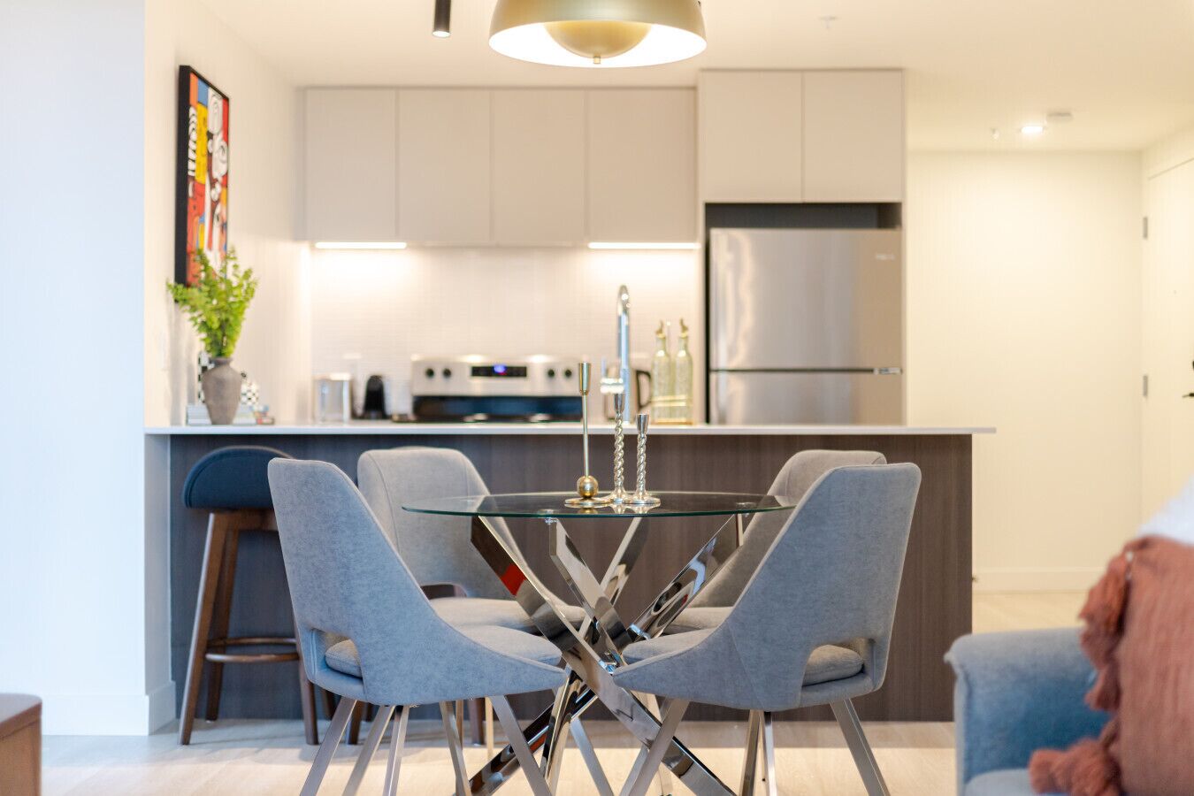A modern kitchen with a central island, bar stools, and a dining table.