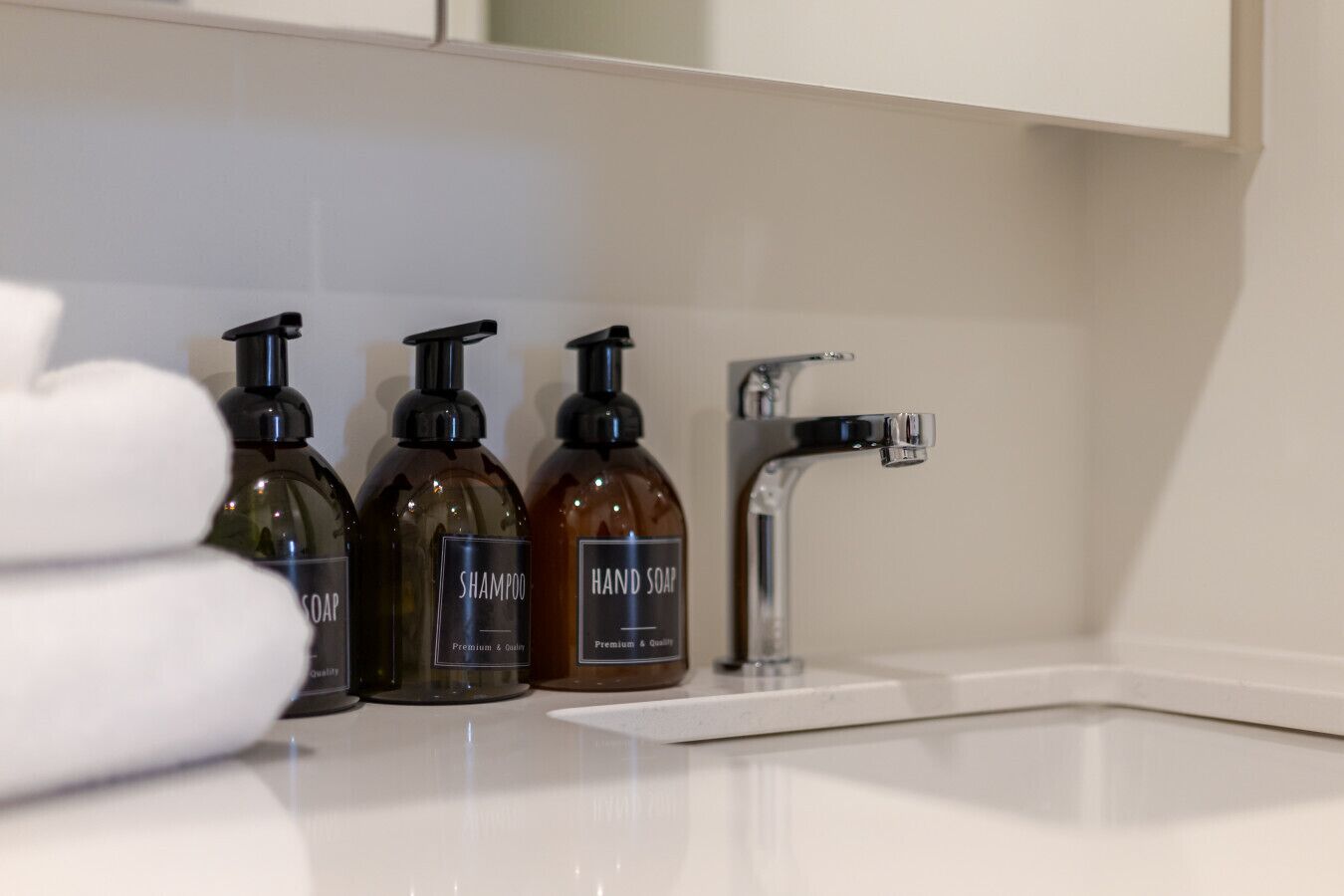 A bathroom with a white sink, three bottles of hand soap, and a faucet.