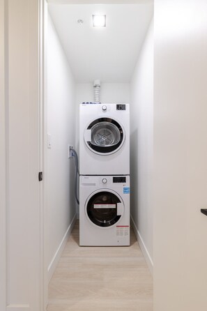 A laundry room with two stacked washing machines and a dryer. - Downtown Prestige | Free Parking (Montréal)