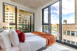 A modern hotel room with a large bed, a balcony, and a city view. - Skyline Retreat | Free Parking & Pool (Montréal)