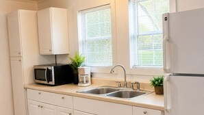 Een moderne keuken met witte kasten, een magnetron, een spoelbak en een koelkast.