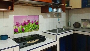 Een keuken met houten kastjes, een gasfornuis, een spoelbak en een betegelde spatwand.