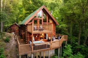 Une cabane en rondins avec un balcon, un jacuzzi et une terrasse.