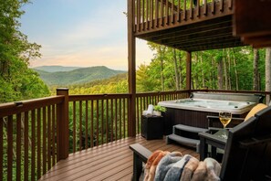 Une terrasse en bois avec un jacuzzi, un verre de vin et une couverture.