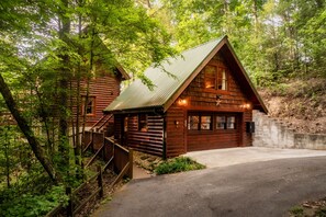 Une cabane en rondins avec un toit en métal, une façade en bois et un escalier menant à l’entrée.