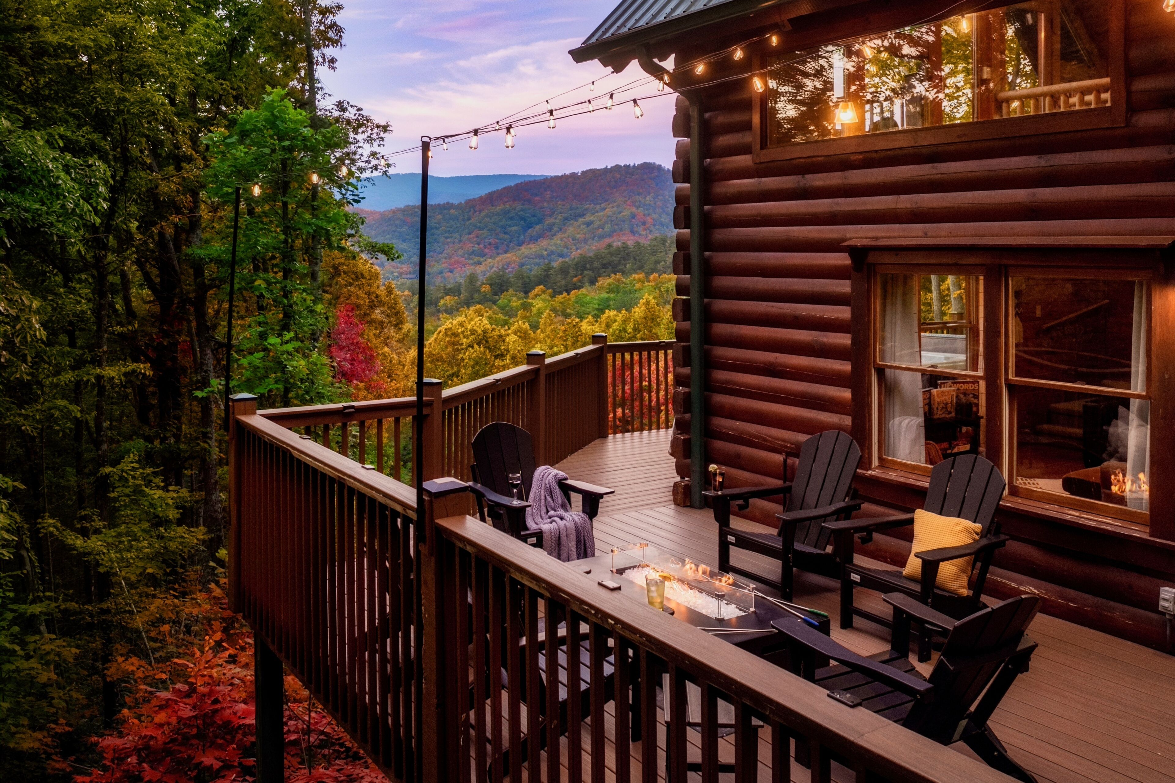 A log cabin with a deck, outdoor seating, and a fire.