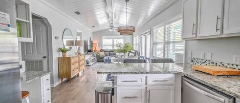 Una cocina amplia con armarios blancos, encimera de granito y una isla central.