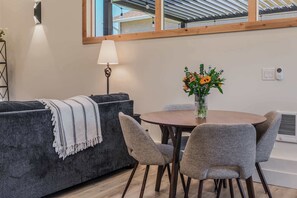 A modern living room with a grey sofa, a round wooden table, and grey chairs. - Cowboy Den by the Creek (Swan Valley)