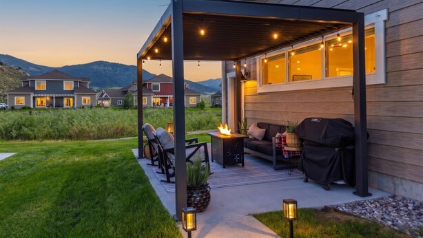 Eine überdachte Terrasse mit Gartenmöbeln, einem Feuerkorb und Lichterketten.