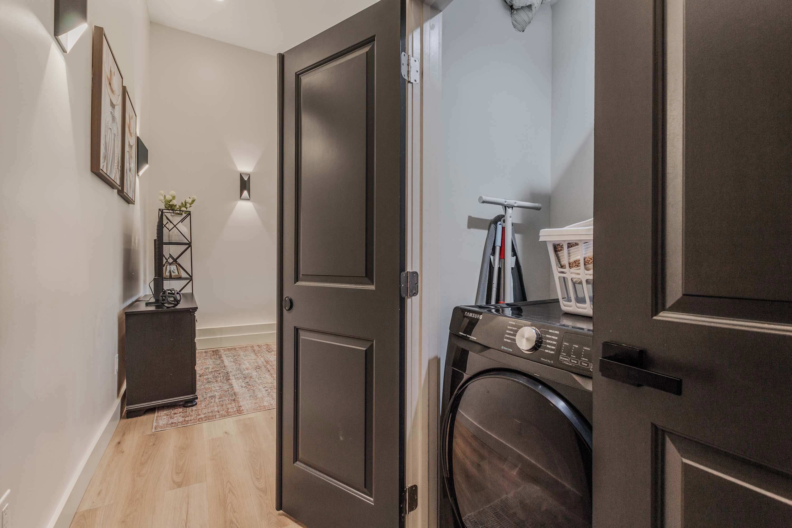 A laundry room with a washing machine, a drying rack, and a small cabinet.