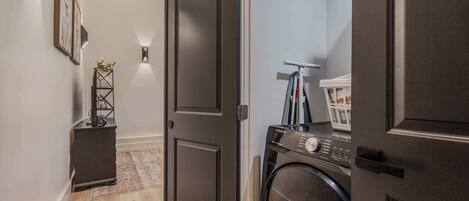 A laundry room with a washing machine, a drying rack, and a small cabinet.