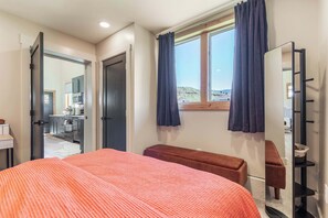 A bedroom with a bed, a bench, a mirror, and a window with curtains. - Cowboy Den by the Creek (Swan Valley)
