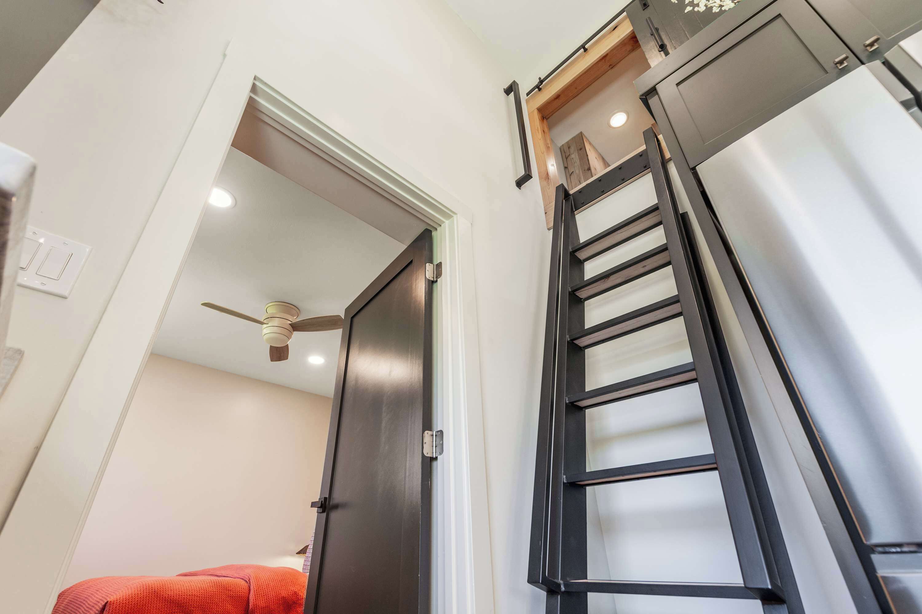 A room with a door leading to another space, a ceiling fan, and a refrigerator.