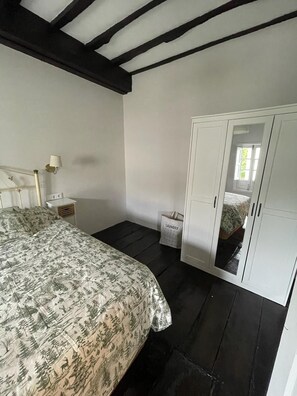 A bedroom with a bed, a nightstand, a lamp, a wardrobe, and a laundry basket. - Your beach and mountain house in Cantabria. (Casar de Periedo)