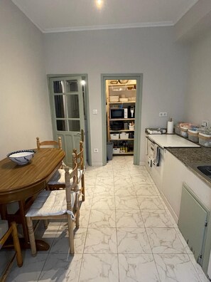 A compact kitchen with a dining area, featuring a wooden table and chairs, a built-in microwave, and a tiled floor. - Your beach and mountain house in Cantabria. (Casar de Periedo)