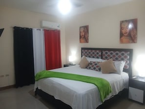 Ein Schlafzimmer mit Bett, Vorhängen, einem Nachttisch und Wandbildern.