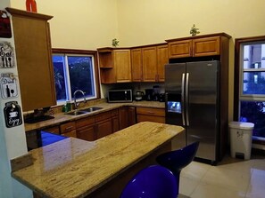 Eine Küche mit Holzausstattung, einem Edelstahlkühlschrank, einer Mikrowelle und einem Spülbecken.