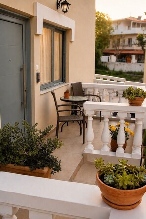 A balcony with a table, chairs, potted plants, and a door. - Yellow Rodon • Modern Studio •3 Min Walk to Beach (Chania)