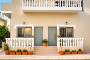 A two-story building with a balcony, a door, and potted plants. - Yellow Rodon • Modern Studio •3 Min Walk to Beach (Chania)