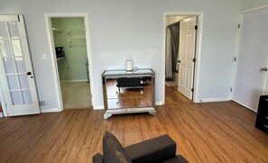 A room with wooden flooring, a mirrored dresser, and a door leading to another room. - 1-bedroom bed & breakfast in charming Cape Coral with Pool and laundry service (Cape Coral)