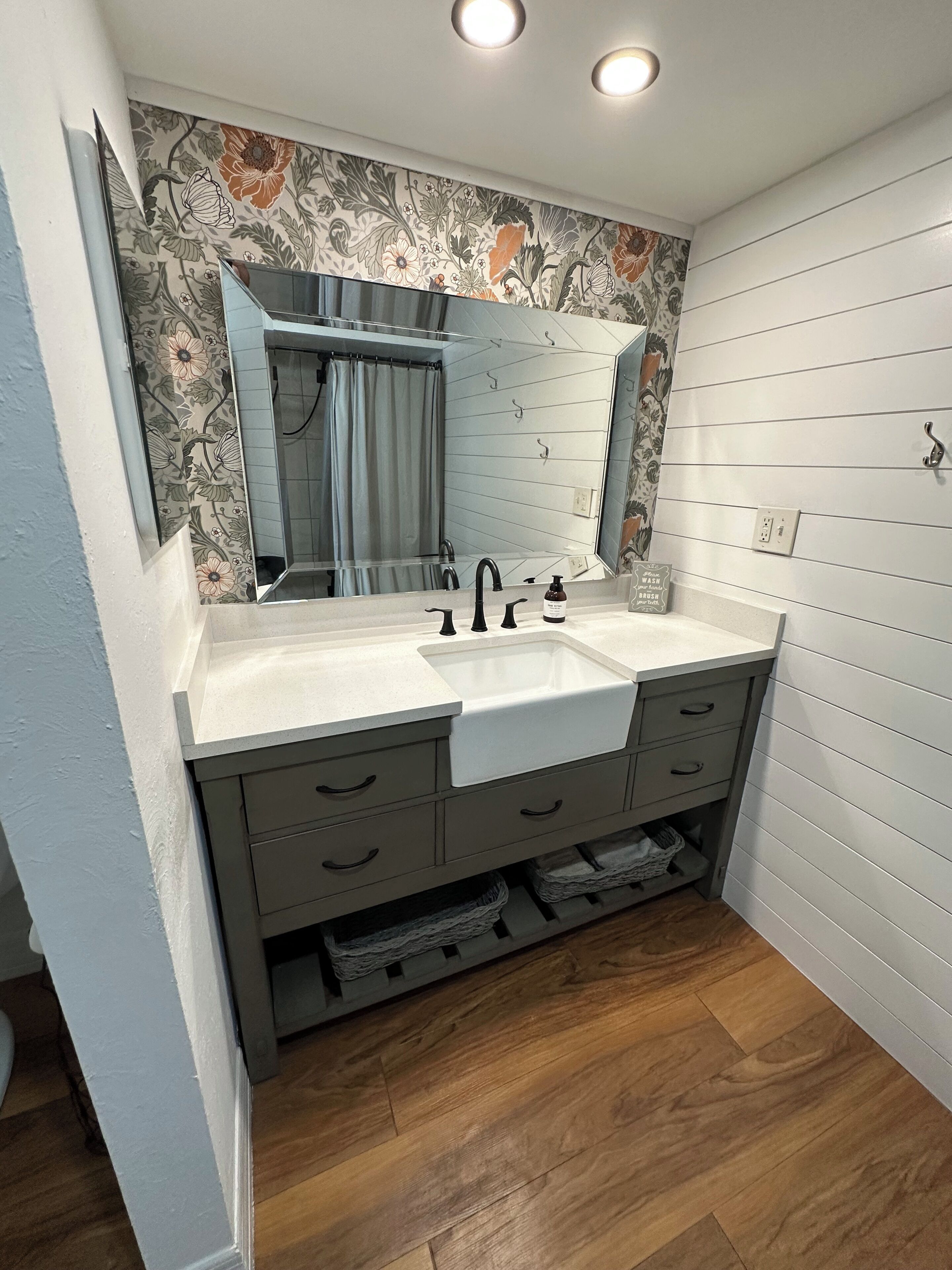 Une salle de bain avec un double lavabo, un miroir et un rideau de douche.
