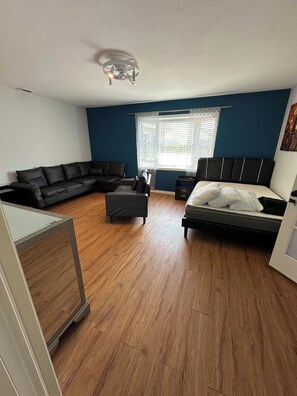 A bedroom with a bed, a sofa, a desk, and a window with patterned curtains. - 1-bedroom bed & breakfast in charming Cape Coral with Pool and laundry service (Cape Coral)