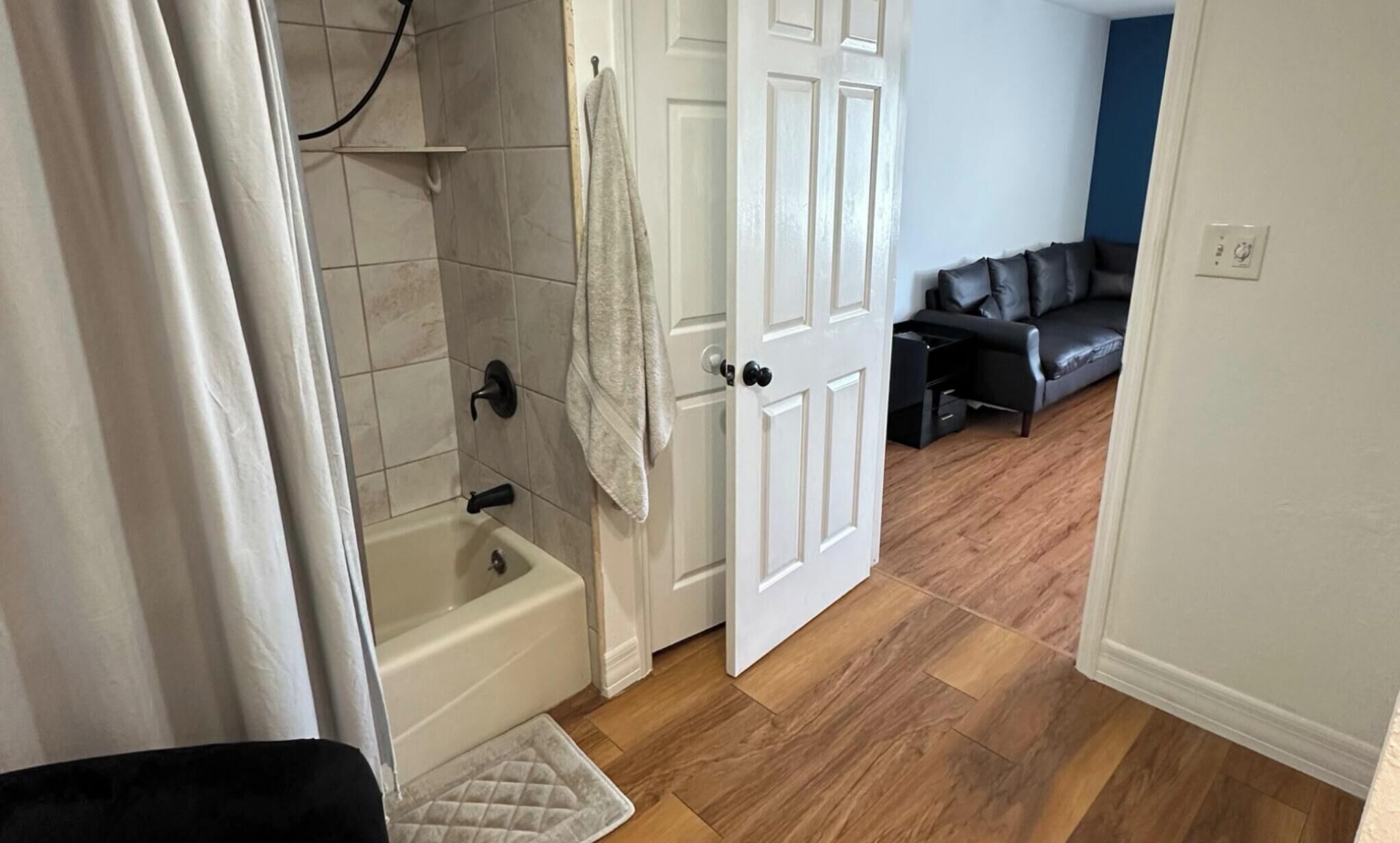A bathroom with a bathtub, a towel hanging on the wall, and a shower curtain partially drawn.