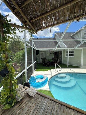 A backyard with a swimming pool, a covered patio, and a fenced area with plants. - 1-bedroom bed & breakfast in charming Cape Coral with Pool and laundry service (Cape Coral)