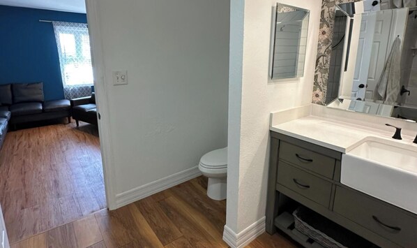 A bathroom with a white sink, dark cabinets, and a large mirror. - 1-bedroom bed & breakfast in charming Cape Coral with Pool and laundry service (Cape Coral)