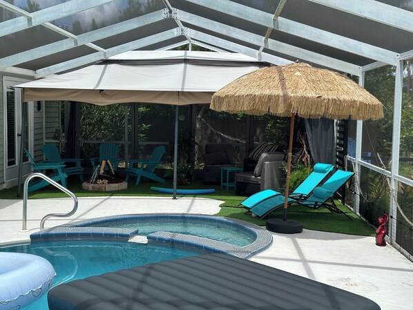 A covered outdoor area with a pool, lounge chairs, and a thatched umbrella.