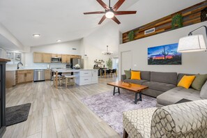 Ein geräumiger Wohnbereich mit Esstisch, Sofa und einer Küche im Hintergrund.