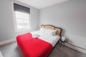 Een slaapkamer met een bed, een raam, een radiator en een kleine tafel.