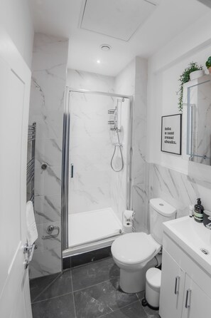 A modern bathroom with a glass-enclosed shower, a toilet, and a sink. - Sun Soaked Brighton 2 Bed Regency Flat - Sea View (Brighton and Hove)