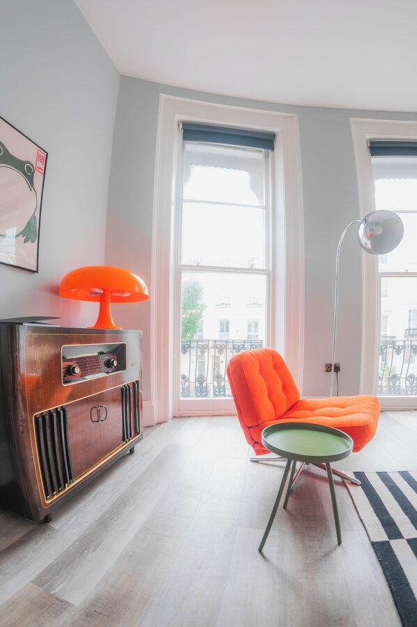 Une pièce avec une radio ancienne, un fauteuil orange moderne et un lampadaire.