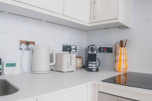 A modern kitchen with a coffee maker, toaster, kettle, and a digital thermometer. - Sun Soaked Brighton 2 Bed Regency Flat - Sea View (Brighton and Hove)