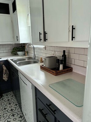 A kitchen with white cabinets, a sink, a toaster, and a coffee maker. - The City Acre- A cozy lil private farmhouse 12 min from Fort Worth and Arlington (Fort Worth)
