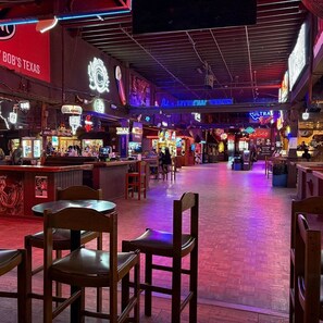 A bar area with wooden chairs and tables, neon signs, and a red carpet. - The City Acre- A cozy lil private farmhouse 12 min from Fort Worth and Arlington (Fort Worth)