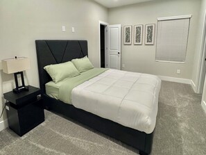 Ein Schlafzimmer mit Bett, Nachttisch, Lampe und Wandbildern.