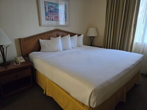 Ein Hotelzimmer mit einem großen Bett, zwei Nachttischen, einer Lampe auf jedem Tisch und einem Bild an der Wand.