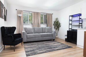 Un salon moderne avec un canapé gris, un fauteuil noir et un tapis noir et gris.