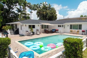 A swimming pool with inflatable rings, a covered patio area, and a small building with a garage. - Social  Studio · Pool · Beach · FLL Airport · Hard Rock · FIFA 2026 · Sleeps 3 (Fort Lauderdale)