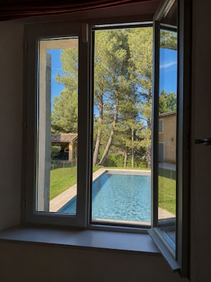A room with a window overlooking a swimming pool and a backyard with trees. - Charming villa in the heart of a golf estate between Luberon and Alpilles (Mallemort)