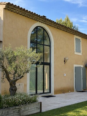 A building with a large arched window, a door, and a small window on the upper right. - Charming villa in the heart of a golf estate between Luberon and Alpilles (Mallemort)