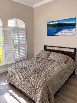 Une chambre à coucher avec un lit, une fenêtre avec des volets et un tableau accroché au mur.