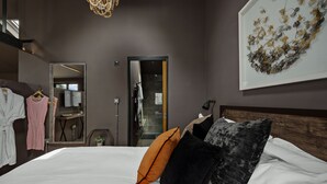 Een hotelkamer met een bed, een spiegel, een kledingkast en een kunstwerk aan de muur.