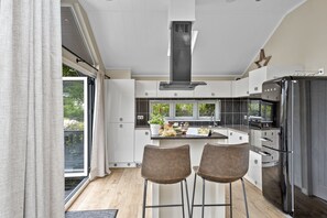 Eine moderne Küche mit einer zentralen Kochinsel, zwei Barhocker und einem großen Fenster.
