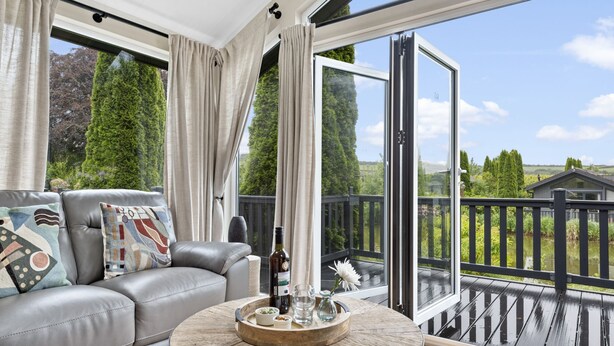 Ein modernes Wohnzimmer mit einer Ledersofa, einem runden Couchtisch und einer großen Glasschiebetür, die auf einen Balkon führt.